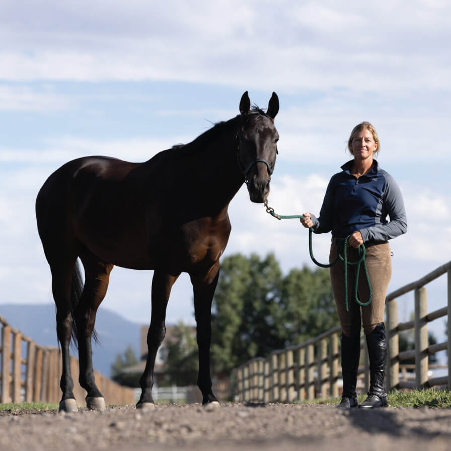 Women standing with a horse on a lead on a trail