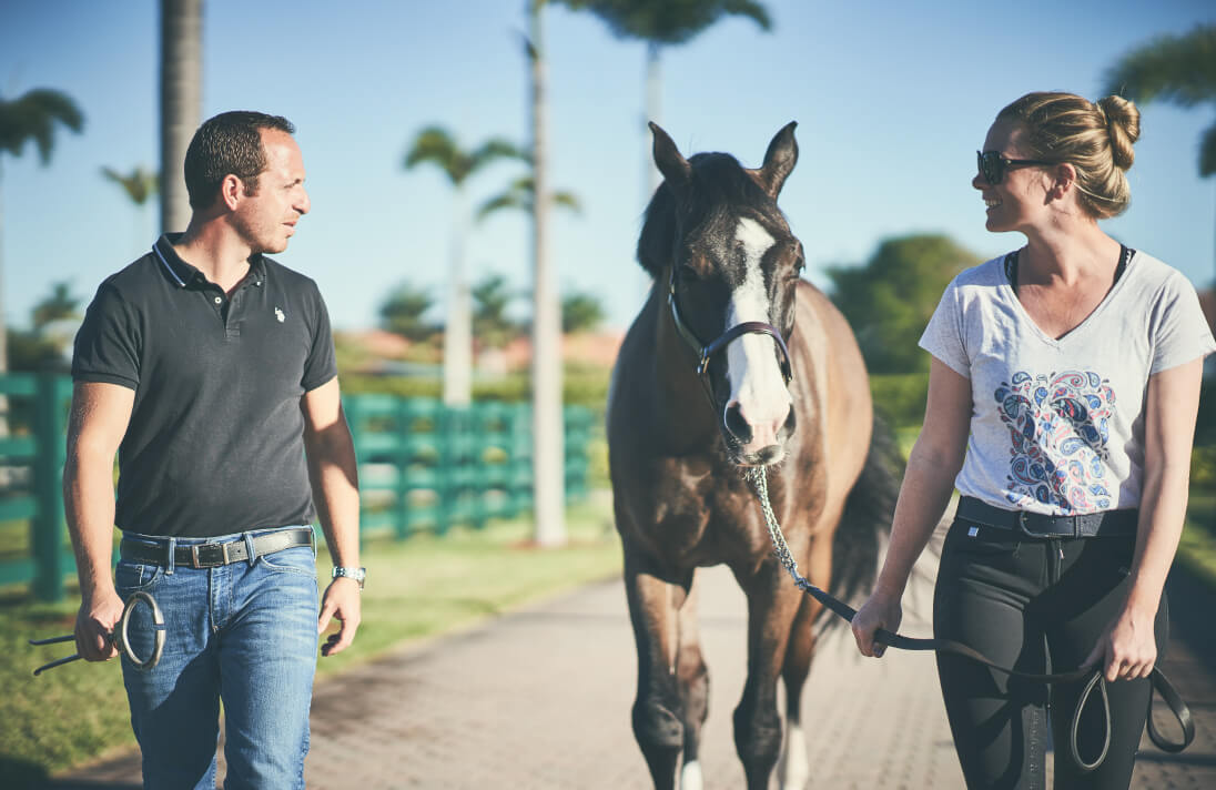 Women and man walking down a path with a horse between them